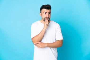 İzole edilmiş mavi arka planı olan beyaz bir adamın şüpheleri ve düşünceleri var.