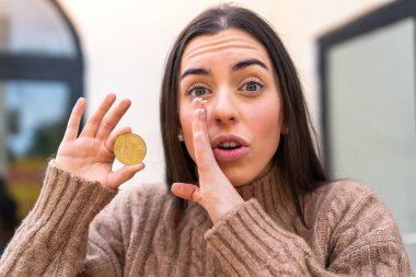 Dışarıda Bitcoin tutan genç bir kadın bir şeyler fısıldıyor