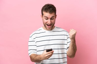 Pembe arka planda izole genç beyaz adam şaşırdı ve bir mesaj gönderiyor.