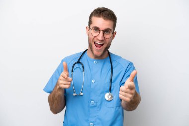 Genç cerrah beyaz arka planda izole edilmiş beyaz bir adam ön tarafı işaret ediyor ve gülümsüyor.