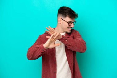 Beyaz tenli yakışıklı adam mavi arka planda izole edilmiş gergin eller öne uzanıyor.