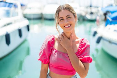 Açık havada genç sarışın bir kadın Neşeli bir ifadeyle