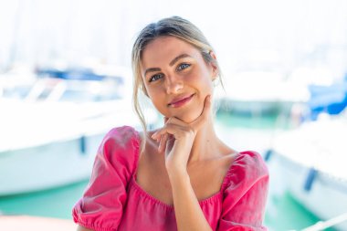 Açık havada gülümseyen genç sarışın kadın.