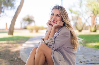 Genç, güzel sarışın Uruguaylı kadın açık havada mutlu bir ifadeyle.