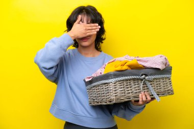 Arjantinli genç bir adam, sarı arka planda, elleri ile gözlerini kapatan bir çamaşır sepeti tutuyor. Bir şey görmek istemiyorum.