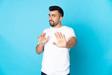 İzole edilmiş mavi arka plan üzerinde beyaz bir adam sinirleri öne doğru geriliyor.