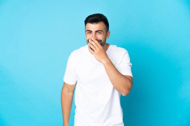 İzole edilmiş mavi arka planda beyaz bir adam mutlu ve gülümsüyor.