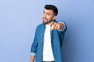 İzole edilmiş mavi arka plan üzerinde beyaz bir adam mutlu bir ifadeyle önü işaret ediyor.