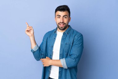 İzole edilmiş mavi arka planı olan beyaz bir adam mutlu ve yukarıya bakıyor.