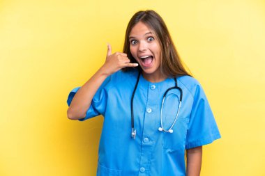 Sarı arka planda izole edilmiş genç bir beyaz kadın telefon jesti yapıyor. Bana geri dönüş işareti ver.