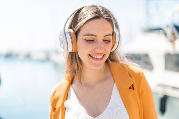 Young pretty woman at outdoors listening music