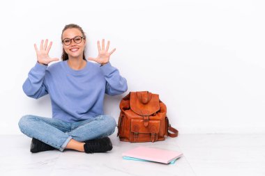 Genç kız beyaz arka planda tek başına oturuyor. Parmaklarıyla 10 kişi sayıyor.