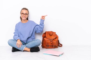 Genç kız, beyaz arka planda izole bir zeminde oturuyor.