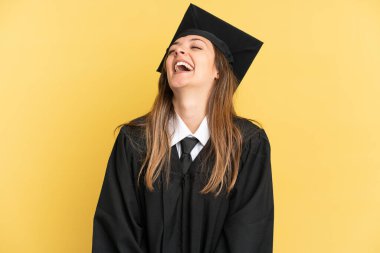 Genç üniversite mezunu, sarı arka planda tek başına gülüyor.