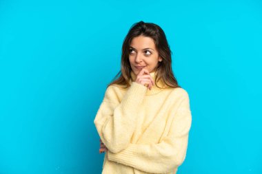 Genç beyaz kadın mavi arka planda izole edilmiş ve yukarı bakıyor.