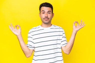 Zen pozisyonunda, izole edilmiş sarı arka planı olan yakışıklı bir genç.