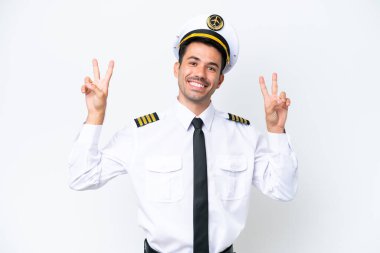 İzole edilmiş beyaz arka planda uçak pilotu iki eliyle zafer işareti gösteriyor.