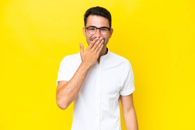 Genç yakışıklı adam izole edilmiş sarı arka planda mutlu ve gülümsüyor.