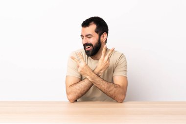 Masada sakallı, gülümseyen ve zafer işareti gösteren beyaz bir adam..