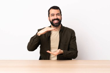 Masada sakallı, beyaz bir adam, bir ilan vermek için avucunda hayali bir fotokopi makinesi tutuyor..