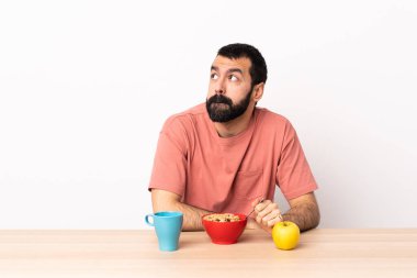 Kafkasyalı bir adam kahvaltı ederken yukarı bakıyor..