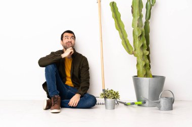 Bahçıvan içeride yerde oturuyor. Şüpheleri var ve düşünüyor.