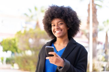 Açık havada cep telefonu kullanan Afrikalı Amerikalı bir kız.