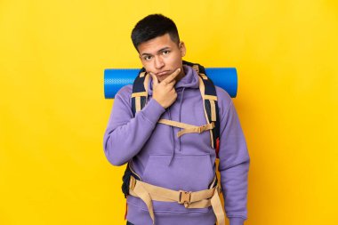 Sarı arka planda izole edilmiş büyük sırt çantalı genç dağcı.