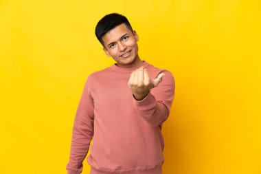 Genç Ekvador 'lu adam sarı arka planda izole edilmiş, bizimle gelmesi için davet ediliyor. Gelmene sevindim.