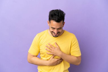 Mor arka planda izole edilmiş genç beyaz adam çok gülümsüyor.