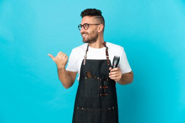 Önlüklü berber bir ürün sunmak için kenarı işaret ediyor.