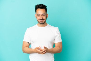 Kafkasyalı genç adam mavi arka planda tek başına gülüyor.