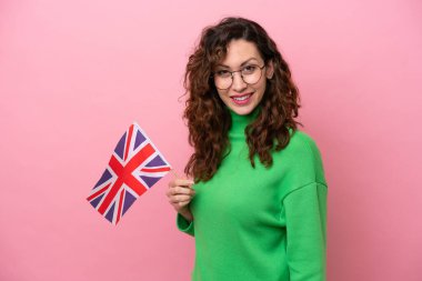 Young caucasian woman holding English flag isolated on pink background smiling a lot