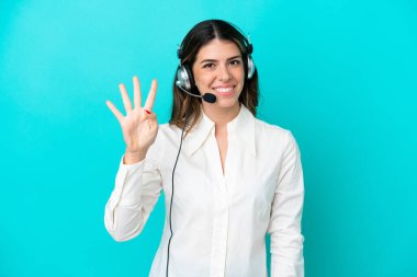 Tele pazarlamacı İtalyan kadın mavi arka planda izole edilmiş kulaklıkla çalışıyor mutlu ve parmakları olan dört kişi sayıyor.