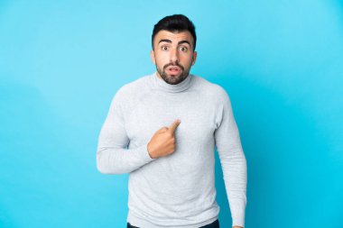 İzole edilmiş mavi arka planı olan beyaz bir adam kendini işaret ediyor.