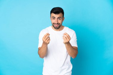 İzole edilmiş mavi arka planda beyaz bir adam para hareketi yapıyor.