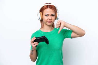Beyaz arka planda izole edilmiş bir bilgisayar oyunu denetleyicisiyle oynayan genç Rus kız negatif ifade ile baş parmağını aşağı gösteriyor