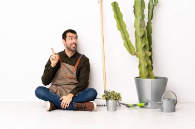 Bahçıvan içeride yerde oturuyor ve parmağını kaldırarak çözümü bulmayı umuyor.