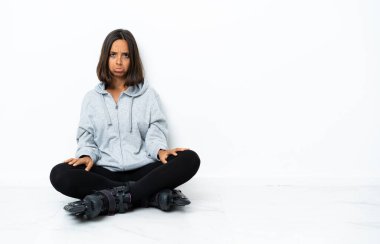 Yerde üzgün yüzüyle paten kayan Asyalı genç bir kadın.