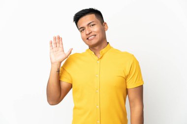 Young Ecuadorian man isolated on white background saluting with hand with happy expression