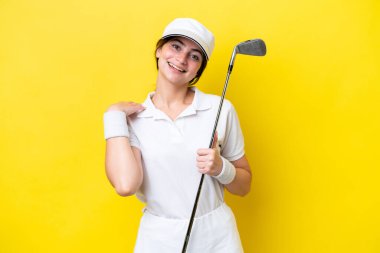 young caucasian woman playing golf isolated on yellow background laughing