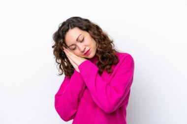 Beyaz arka planda izole edilmiş genç beyaz kadın uyku jesti yapıyor.