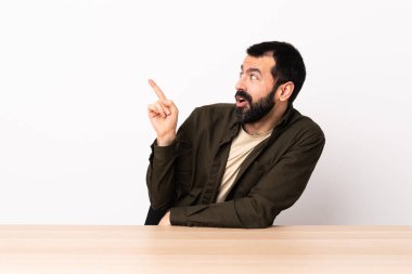 Masada sakallı, beyaz bir adam parmağını kaldırarak çözümü bulmaya çalışıyor..