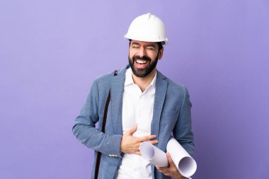 Miğferli genç bir mimar ve izole edilmiş mor arkaplanının planlarını tutuyor.