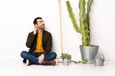 Bahçıvan içeride yerde oturmuş bir fikir düşünüyor.