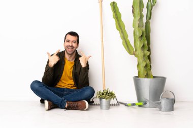 Bahçıvan içeride yerde oturuyor ve baş parmak işareti yapıyor.