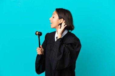 İzole edilmiş mavi arka planda yargıçlık elini kulağına koyarak bir şeyler dinlemektir.