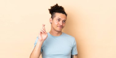 İzole edilmiş arka planda beyaz bir adam parmaklarını çapraz yapıp en iyisini diliyor.