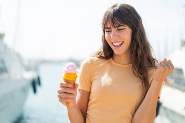 Kornet dondurmalı genç bir kadın dışarıda zaferi kutluyor.