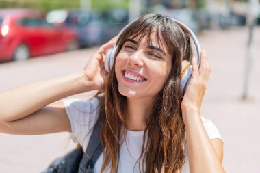 Açık havada müzik dinleyen genç bir kadın